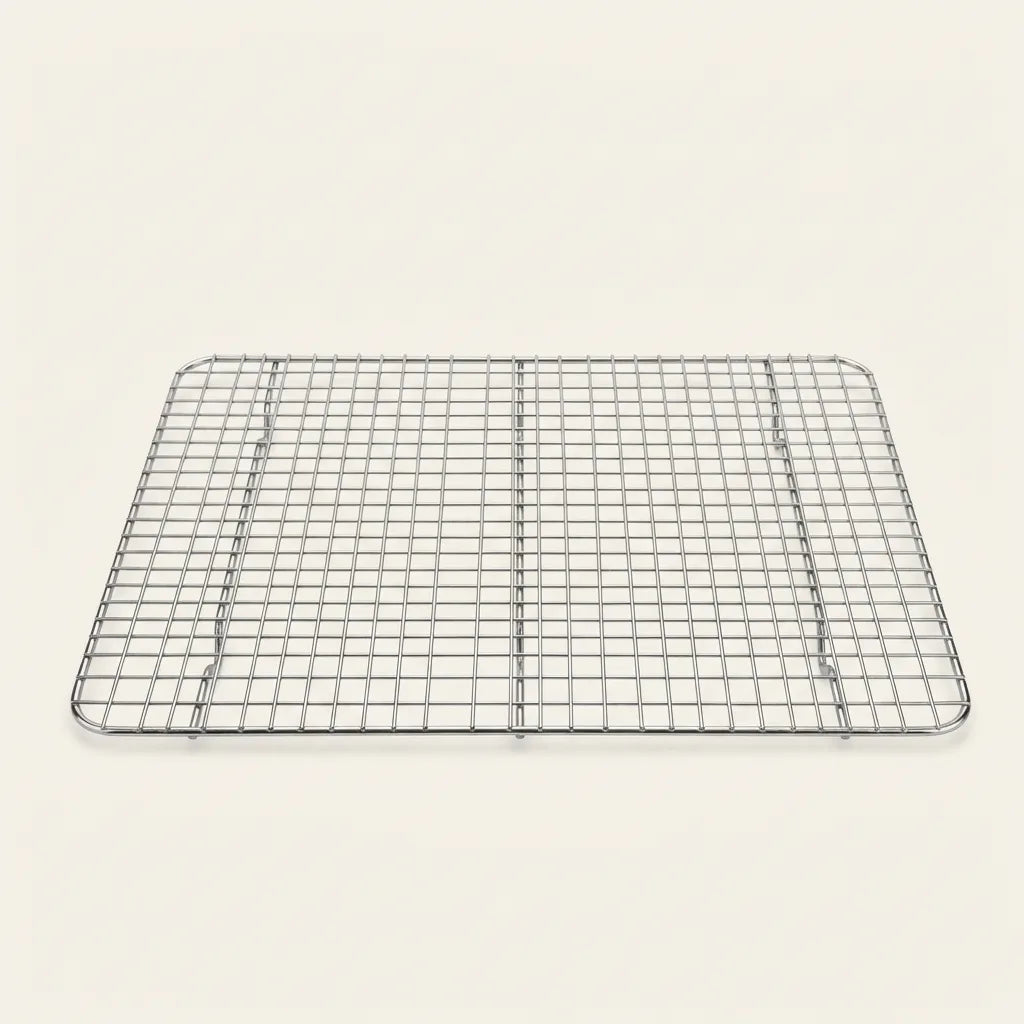 Rektangulær afkølingsrist i rustfrit stål med ternet mønster og små fødder, vist på lys baggrund i et fotostudie.